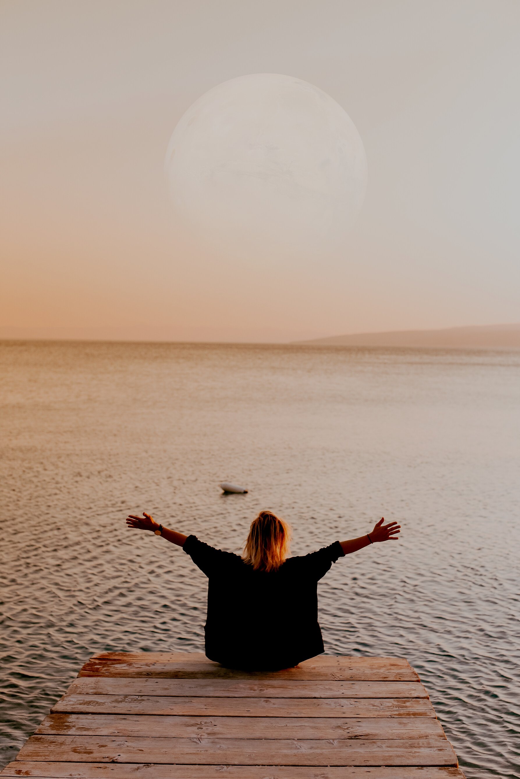 Woman Sitting on a Pier and Looking at the Moon